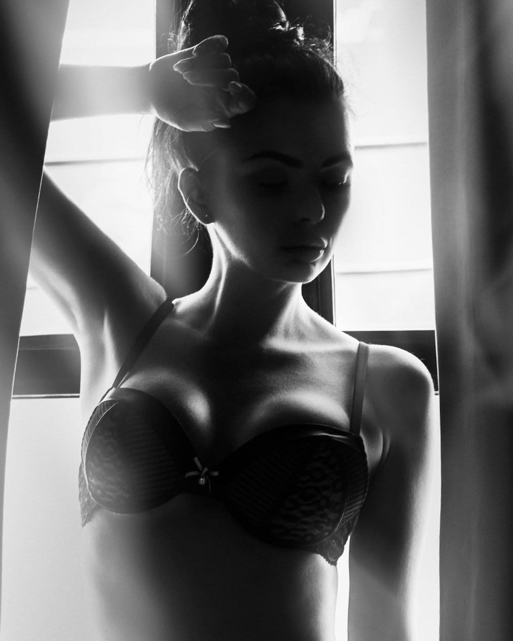 New Jersey Breast Implant patient model in a bra standing in front of a window